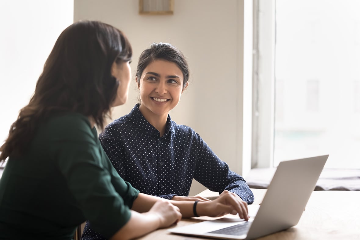 Smiling young woman intern learn from female mentor at workplace.