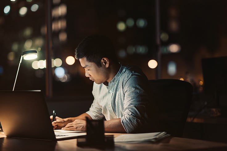 a man sitting at his desk at nightime working late