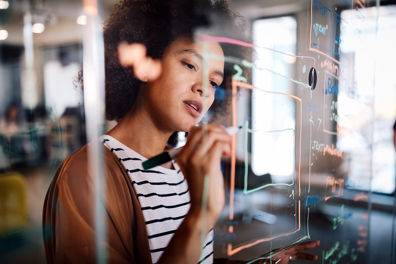 Woman working and writing on the glass board in office
