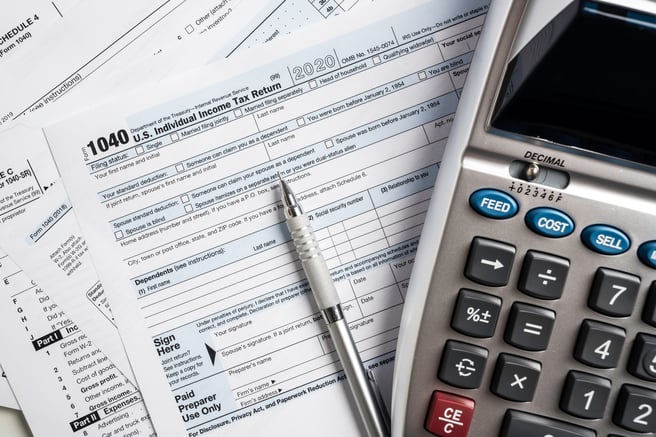 Tax forms, a mechanical pencil, and a calculator.