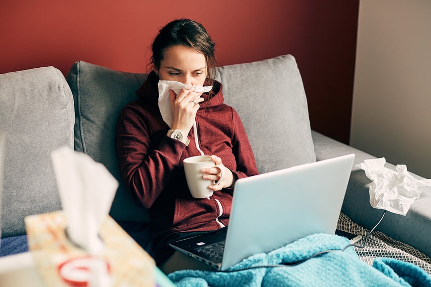a woman sitting in bed sick while working remotely