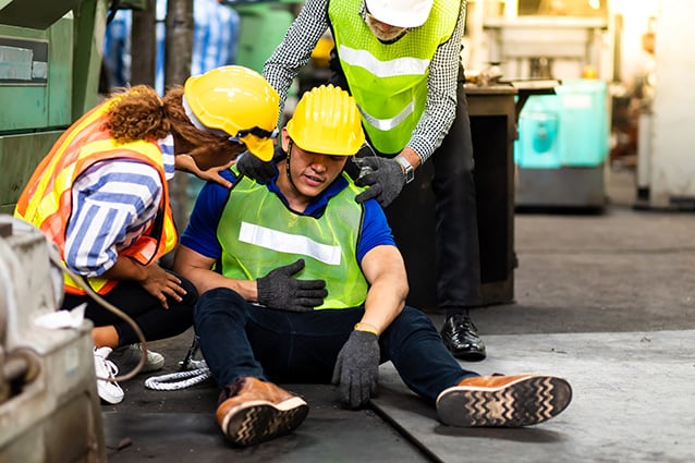 First Aid. Engineering supervisor talking on walkie talkie communication while his coworker lying unconscious at industrial factory. Professional engineering teamwork concept