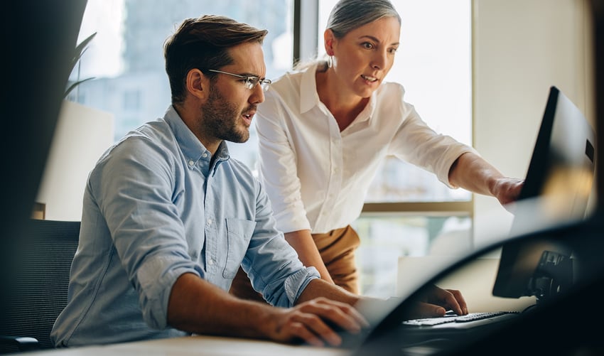a businessman and woman looking at a computer.