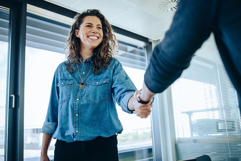 A businesswoman shaking hands with a businessman.