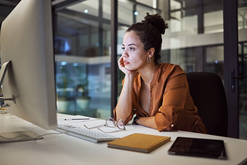 a corporate woman in an office at her desk looks at her computer