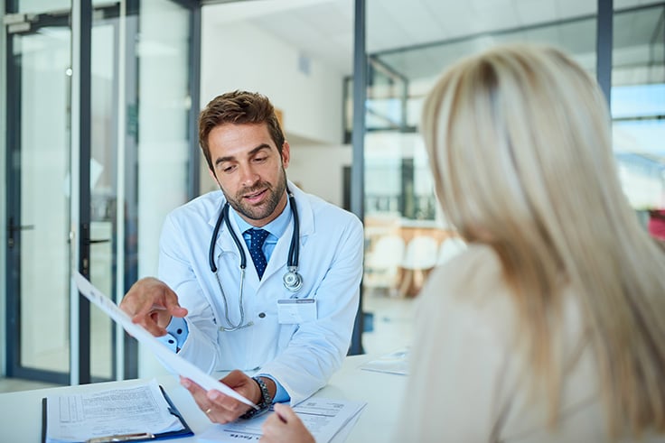 a male doctor discusses with a female patient.