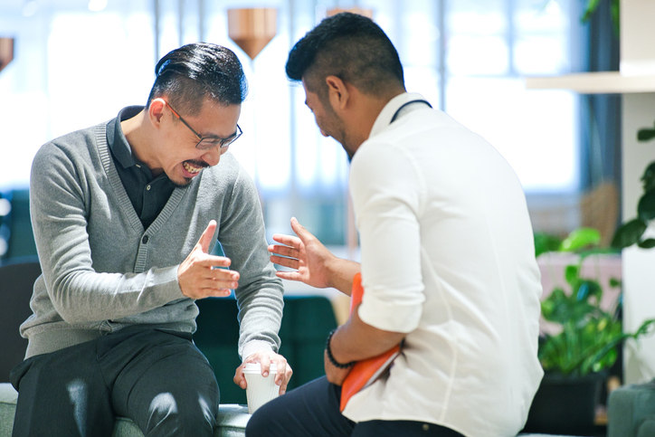 two guys sit down and high five each other.