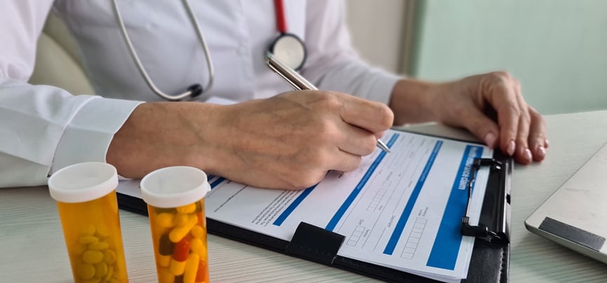 a doctor writes out a prescription on a clipboard