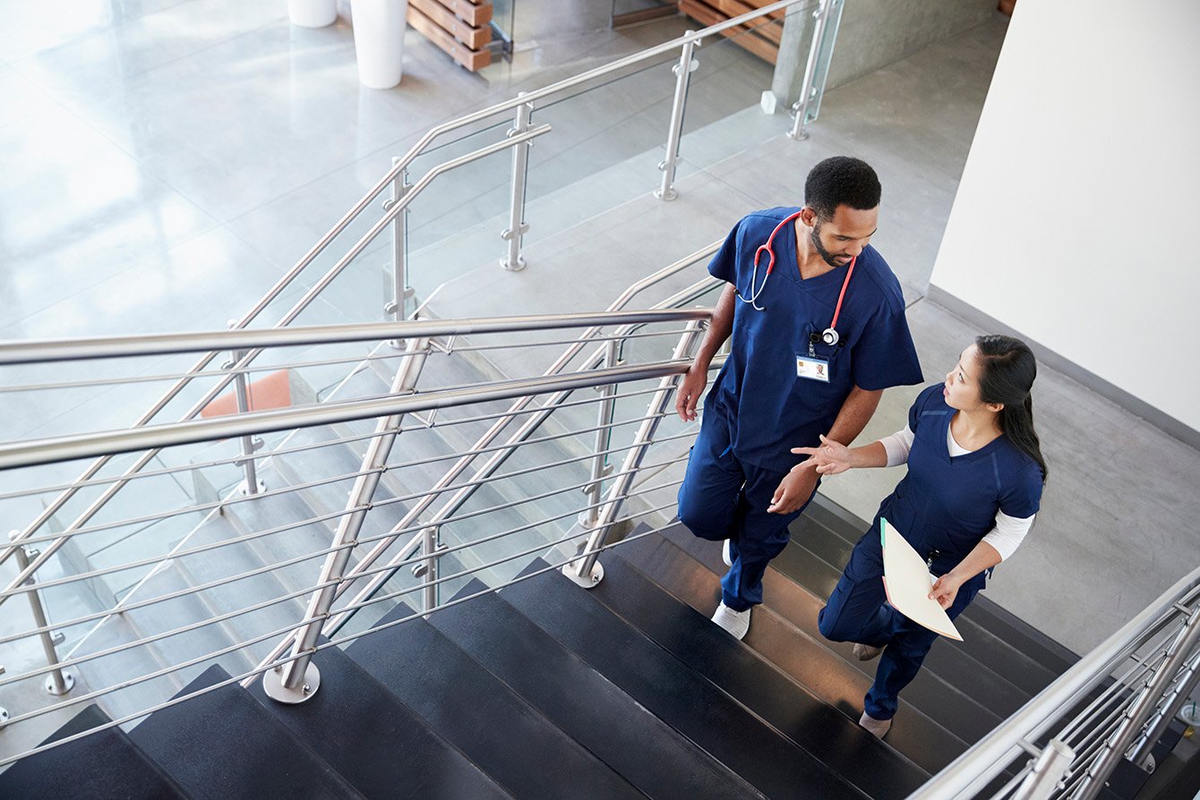 two hospital workers walk up the stairs together.