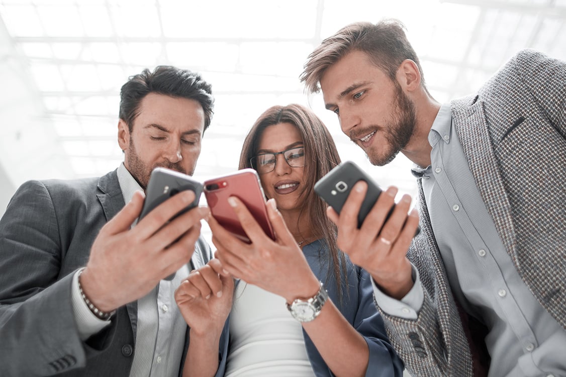 three-work-colleagues-look-down-at-each-others-phones