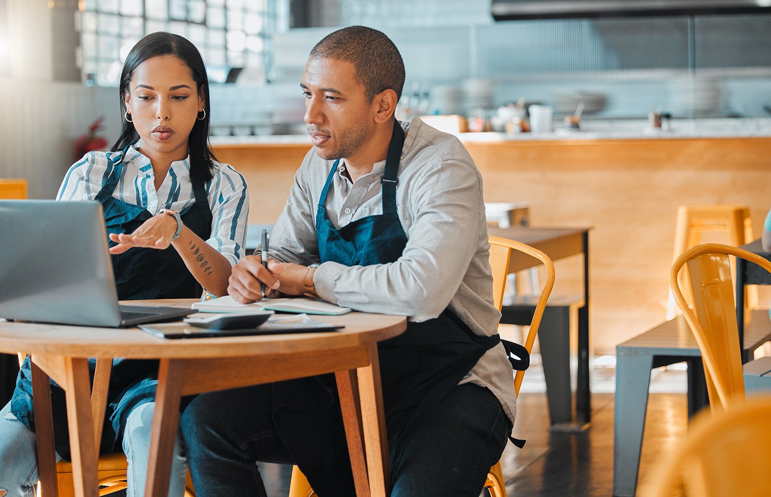 two restaurant workers sitting at a table discussing numbers before service.