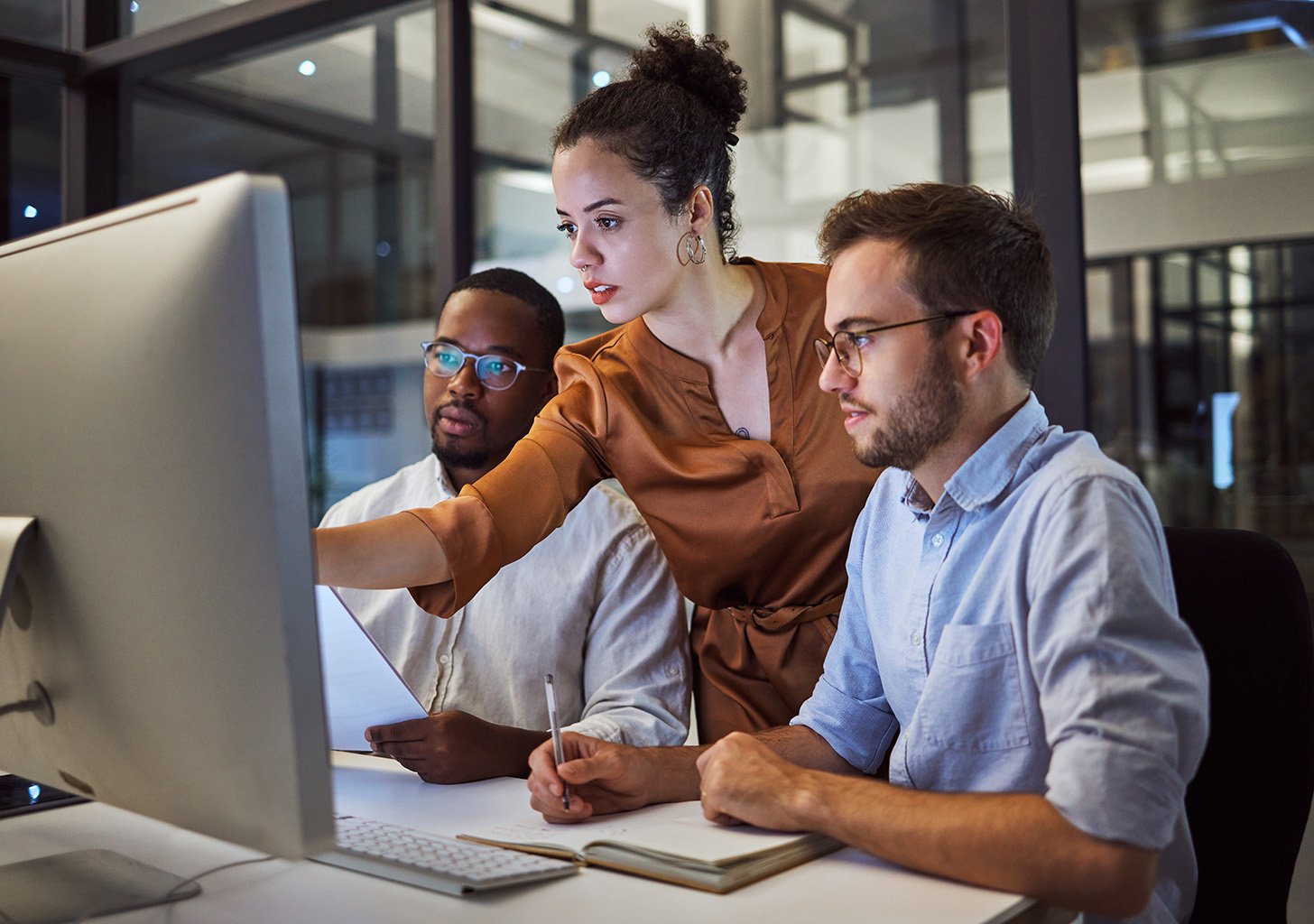 three corporate people look at a computer focused and serious.