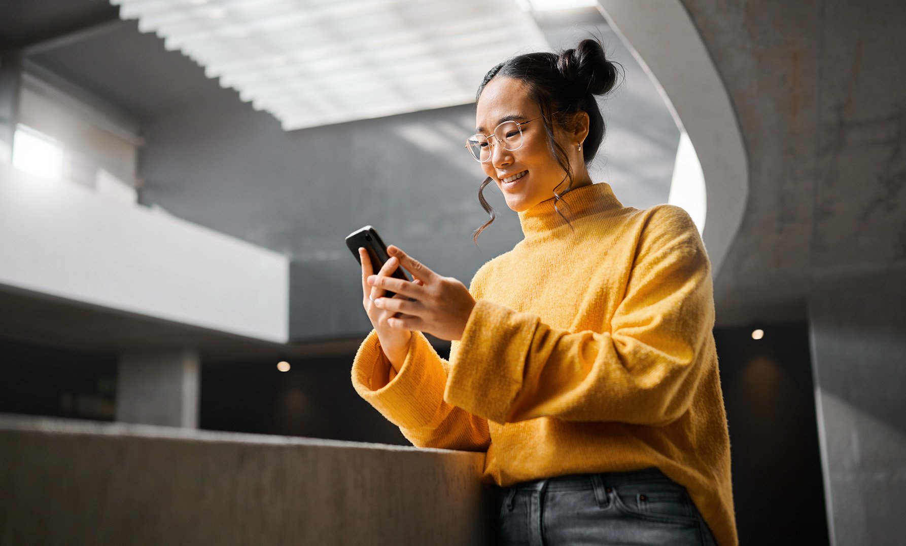 a woman standing in an office building using her smartphone.