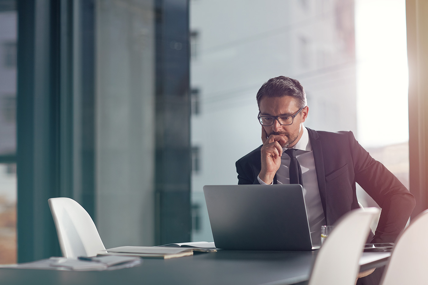 a-man-sits-at-a-conference-table-and-looks-pensively-at-his-laptop