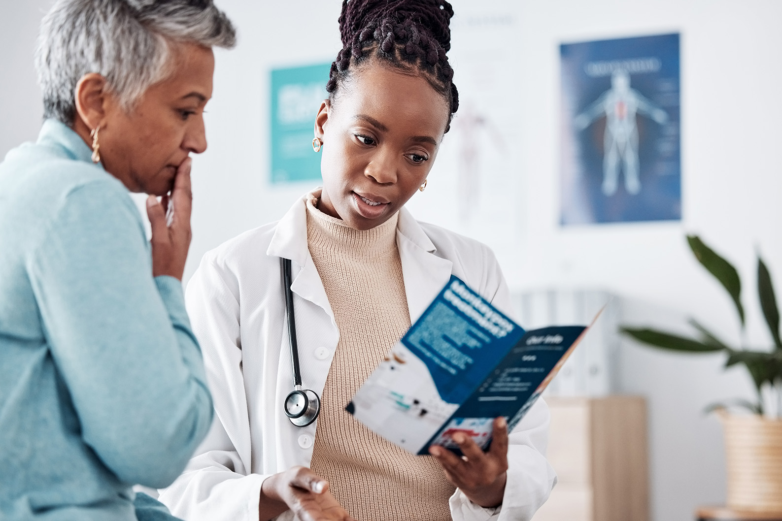 a female doctor talks to a female patient about information in a brouchure. 