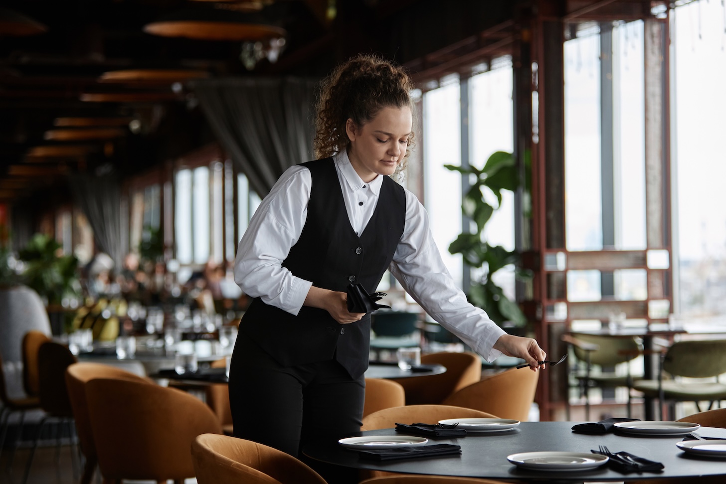 a female server setting a table in an empty restaurant