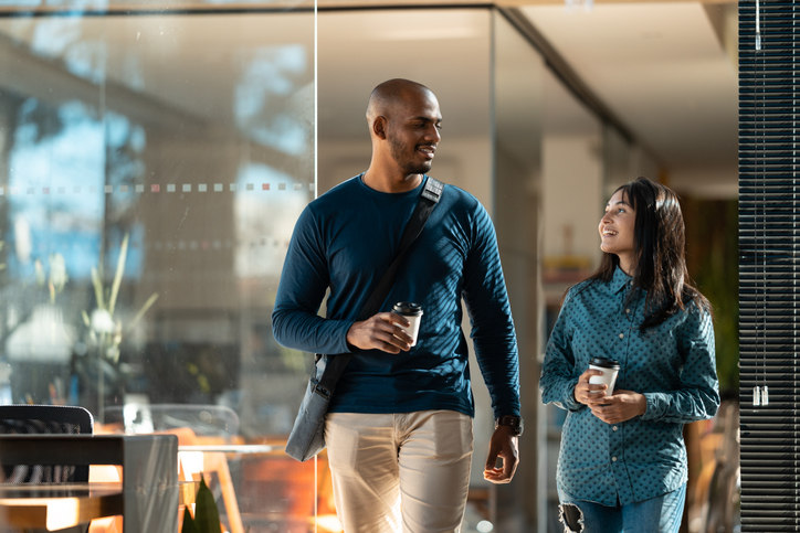 two corporate coworkers walk together in an office one male and one female.